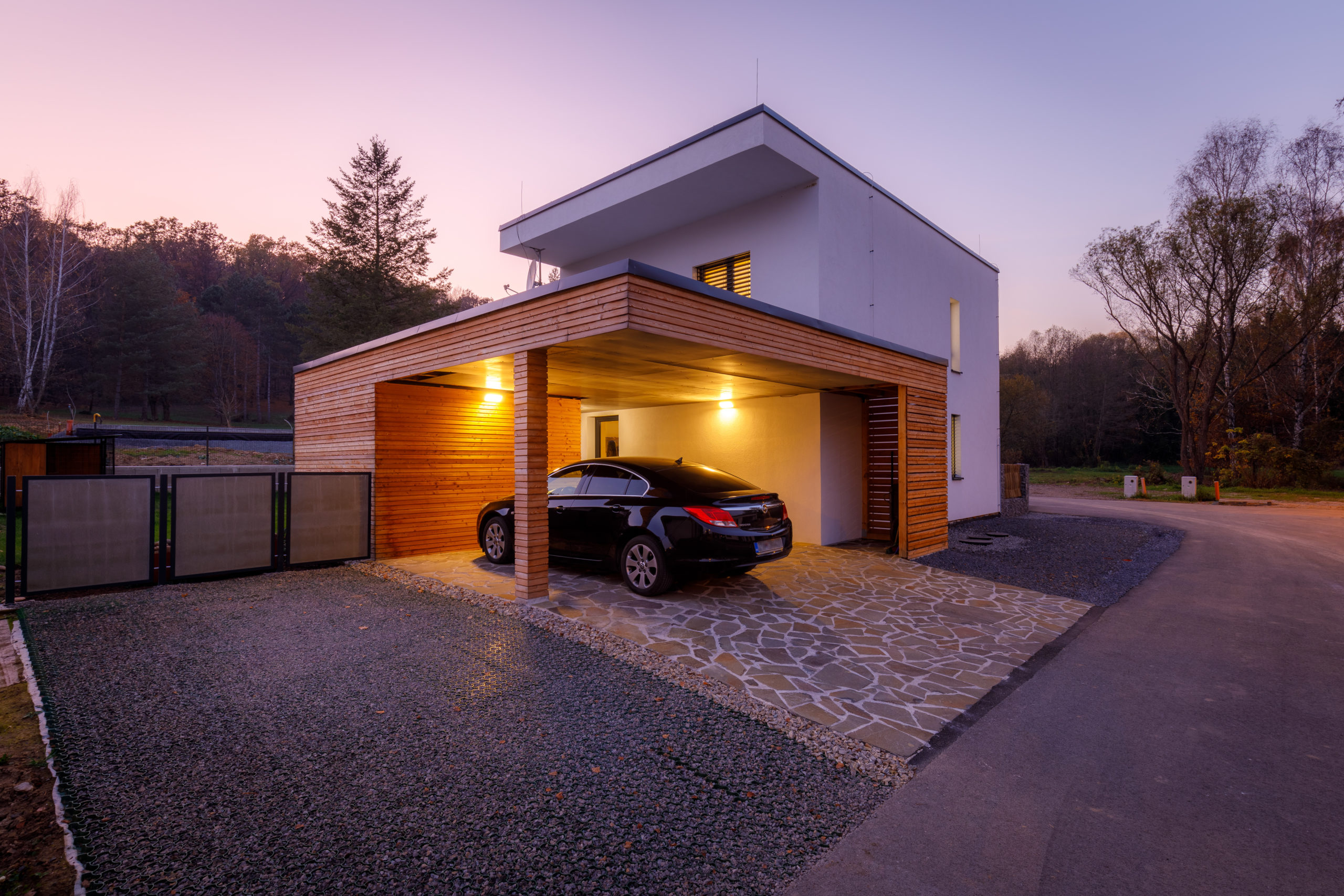 Build With Nature Kit Homes Prefab house exterior at dusk with car parked under carport
