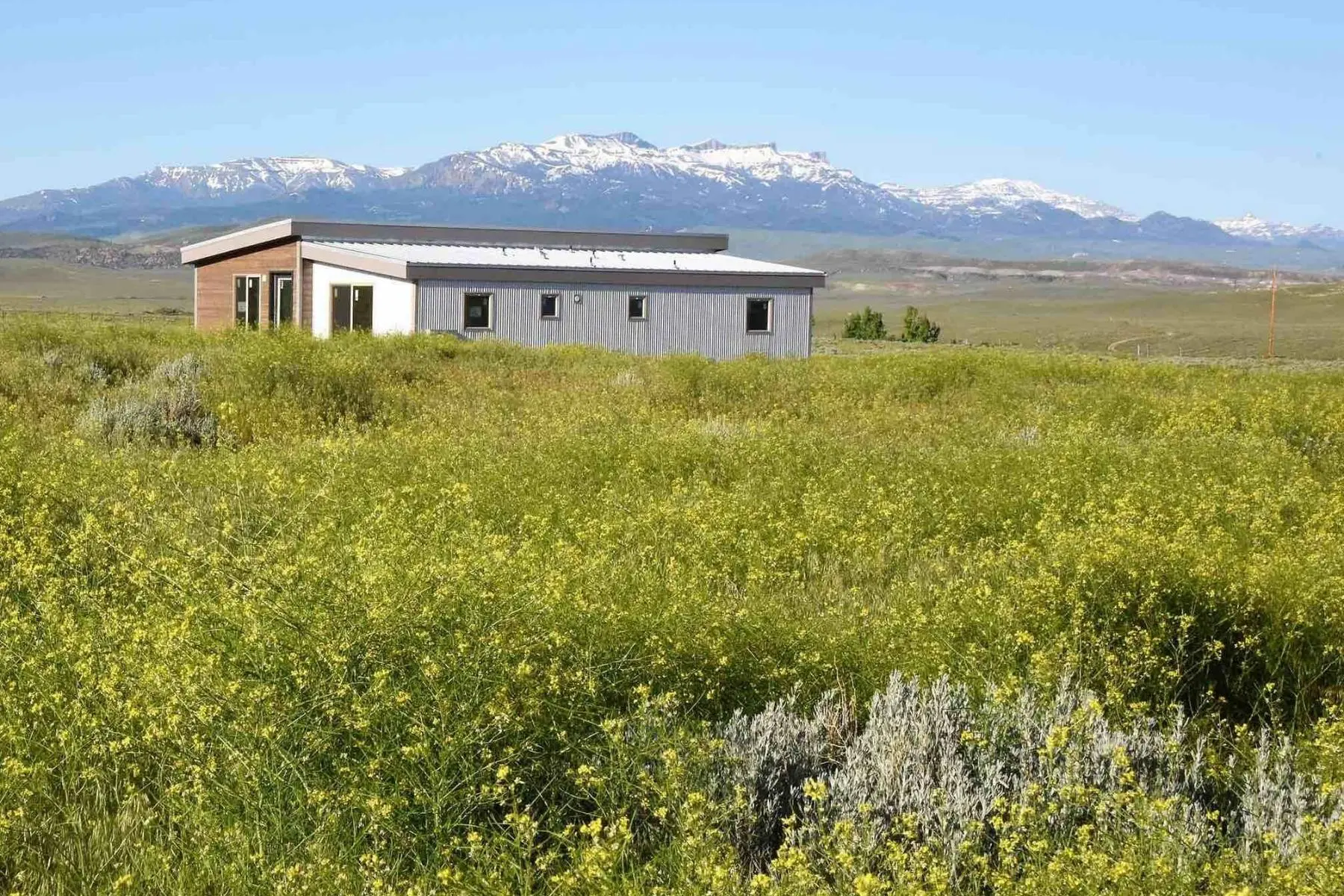 IdeaBox Sage House sustainable prefab housing IdeaBox Sage House sustainable prefab housing out in a field with mountains in the distance